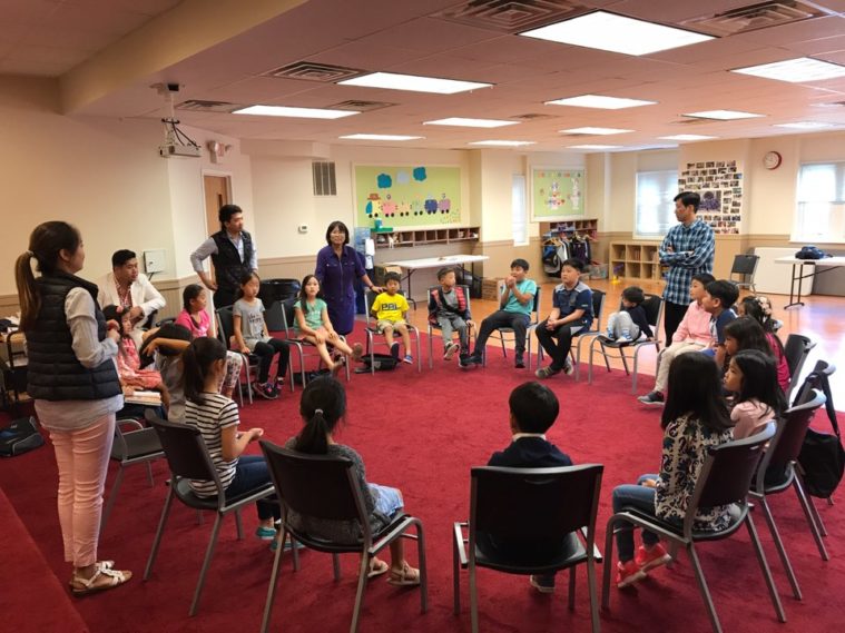 Bunch of children are seating on chairs.